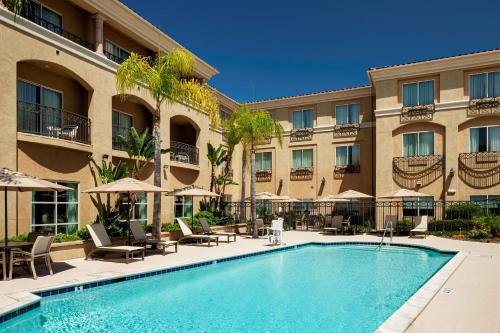 a pool in front of a hotel with chairs and umbrellas at Hilton Garden Inn San Diego/Rancho Bernardo in Rancho Bernardo