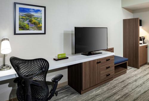 a hotel room with a desk with a television and a chair at Hilton Garden Inn San Diego/Rancho Bernardo in Rancho Bernardo