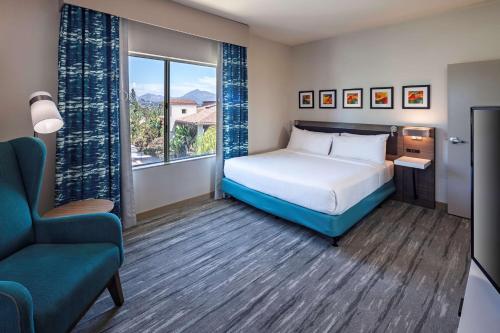 a bedroom with a bed and a chair and a window at Hilton Garden Inn San Diego/Rancho Bernardo in Rancho Bernardo