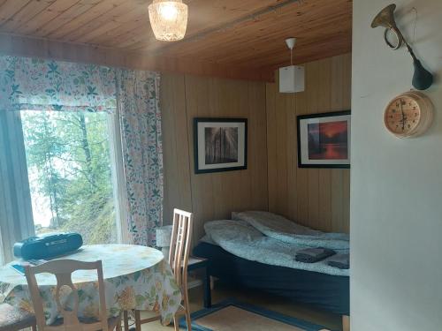 a room with a table and a bed and a window at Lakeside Hilda, rantamökki 