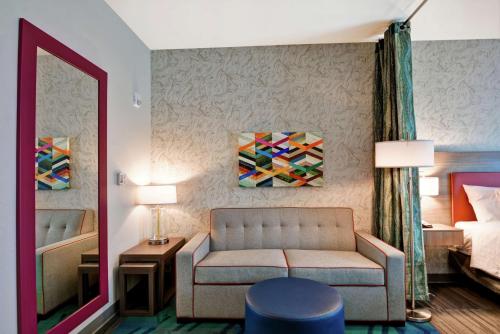a room with a couch and a bed and a mirror at Home2 Suites By Hilton Daytona Beach Speedway in Daytona Beach