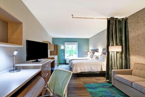 a hotel room with a bed and a television at Home2 Suites By Hilton Daytona Beach Speedway in Daytona Beach