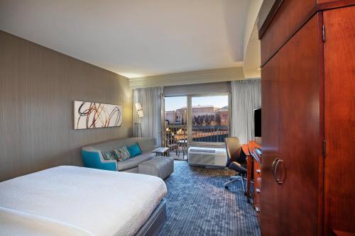 a hotel room with a bed and a living room at Courtyard by Marriott Dallas Allen at Allen Event Center in Allen