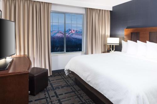 a hotel room with a large bed and a window at Embassy Suites Anchorage in Anchorage