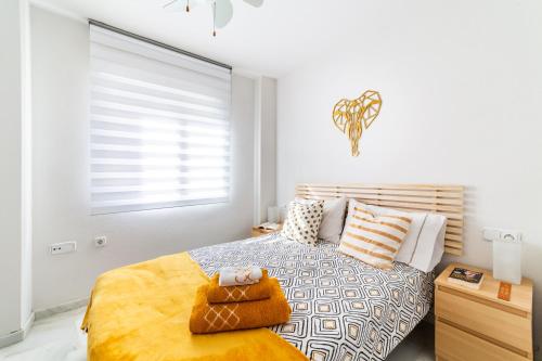 a white bedroom with a bed and a window at Apartamento cerca de una de las mejores playas. in Roquetas de Mar