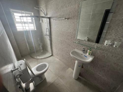 ein Bad mit einer Dusche, einem WC und einem Waschbecken in der Unterkunft J2 Villa in Sukuta