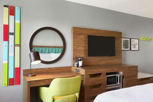 a bedroom with a tv and a chair and a mirror at Hampton Inn & Suites Fort Lauderdale Airport in Hollywood