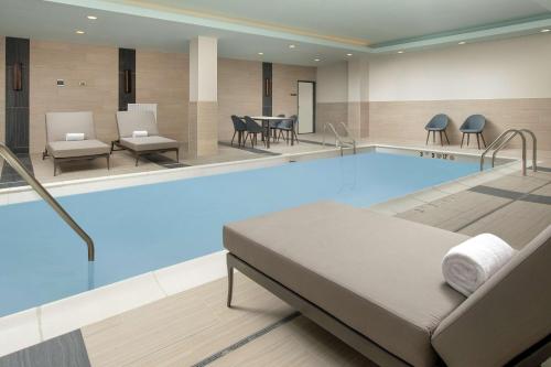 a pool in a hotel room with a bed and chairs at Hilton Garden Inn Westchester Dobbs Ferry in Dobbs Ferry