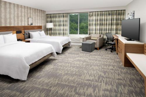 a hotel room with two beds and a flat screen tv at Hilton Garden Inn Westchester Dobbs Ferry in Dobbs Ferry