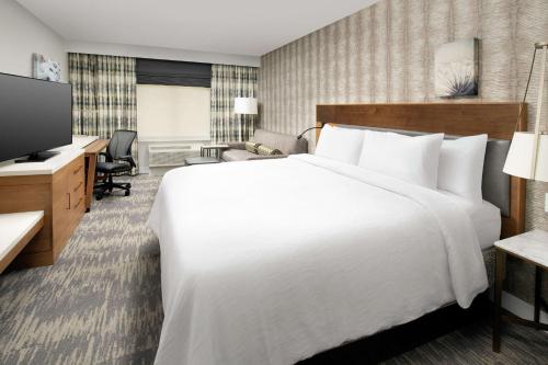 a hotel room with a large white bed and a desk at Hilton Garden Inn Westchester Dobbs Ferry in Dobbs Ferry