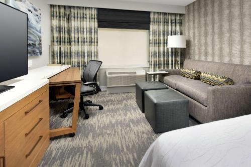 a hotel room with a bed and a desk and a couch at Hilton Garden Inn Westchester Dobbs Ferry in Dobbs Ferry