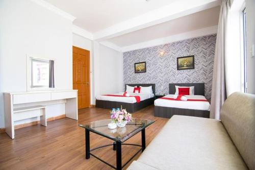 ein Hotelzimmer mit 2 Betten und einem Tisch in der Unterkunft Quynh Giang Hoang Viet in Ho-Chi-Minh-Stadt