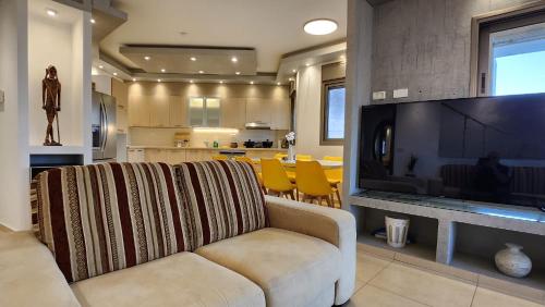 a living room with a couch and a large television at Roy Vacation Home in Rishon LeẔiyyon