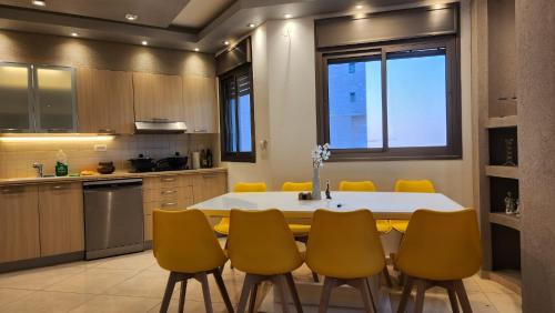 a kitchen with a dining table and yellow chairs at Roy Vacation Home in Rishon LeẔiyyon