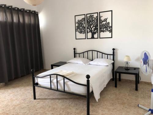ein Schlafzimmer mit einem Bett und zwei Bildern an der Wand in der Unterkunft Tarrafal Ecodécor Rooms in Tarrafal