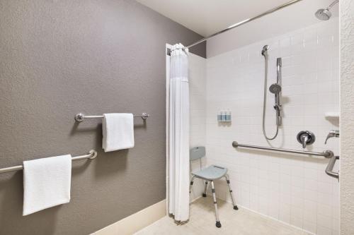 y baño con ducha y silla. en Courtyard by Marriott Daytona Beach Speedway/Airport en Daytona Beach