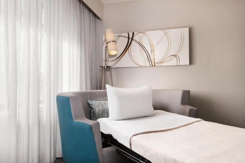 a room with a bed and a chair and a lamp at Courtyard by Marriott Daytona Beach Speedway/Airport in Daytona Beach