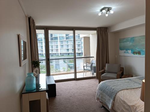 a bedroom with a bed and a chair and a window at 501 Canal Quays in Cape Town