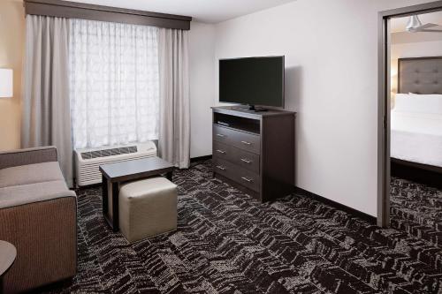 a hotel room with a bed and a flat screen tv at Homewood Suites By Hilton Ronkonkoma in Ronkonkoma