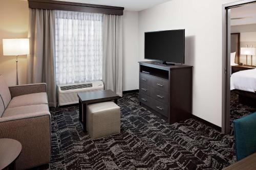 a hotel room with a bed and a flat screen tv at Homewood Suites By Hilton Ronkonkoma in Ronkonkoma