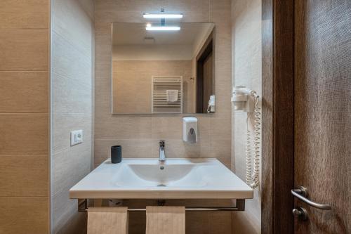 bagno con lavandino bianco e specchio di Hotel Ristorante Il Caminetto a Diano Marina