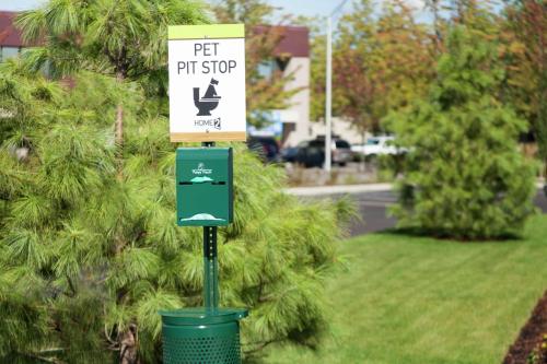 a sign on a pole with a trash can at Home2 Suites by Hilton Seattle Airport in Tukwila