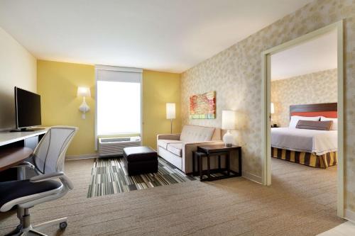 a hotel room with a bedroom with a bed and a desk at Home2 Suites by Hilton Seattle Airport in Tukwila