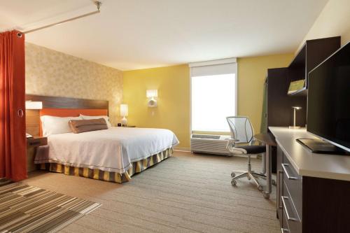 a hotel room with a bed and a flat screen tv at Home2 Suites by Hilton Seattle Airport in Tukwila