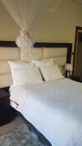 a white bed with white sheets and pillows at Broadhurst Homestay in Gaborone