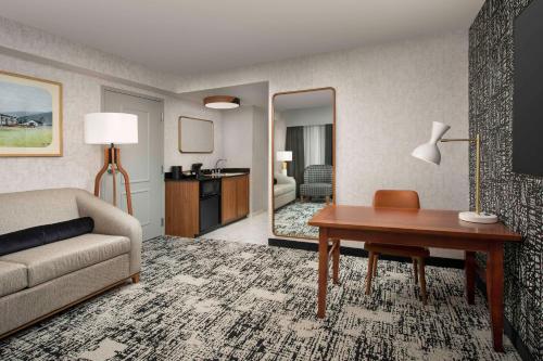 a living room with a couch and a table and a mirror at Embassy Suites by Hilton Dulles North Loudoun in Ashburn