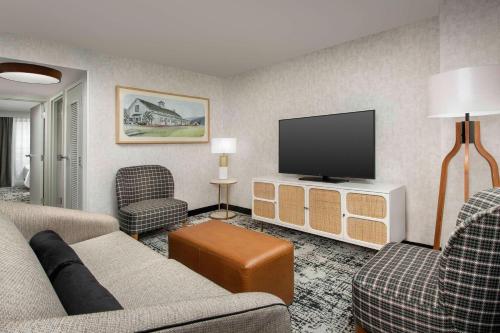 a living room with a couch and a flat screen tv at Embassy Suites by Hilton Dulles North Loudoun in Ashburn