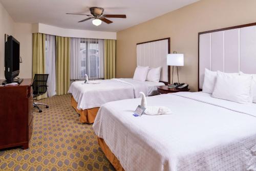 a hotel room with two beds and a flat screen tv at Homewood Suites by Hilton Jacksonville-Downtown/Southbank in Jacksonville