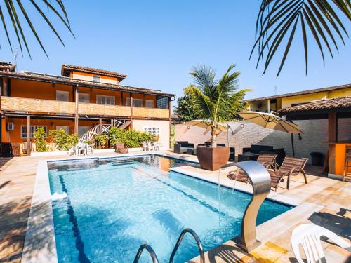 a swimming pool with chairs and a building at VELINN Pousada Face Norte in Ilhabela
