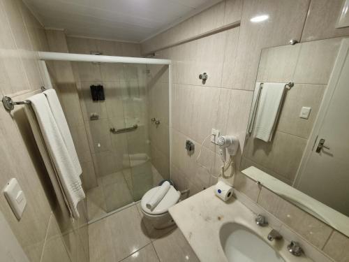 a bathroom with a shower and a toilet and a sink at Marambaia Hotel e Convenções in Balneário Camboriú