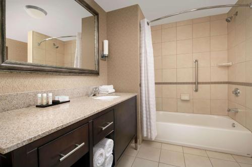 a bathroom with a sink and a tub and a mirror at Embassy Suites by Hilton Birmingham Hoover in Hoover