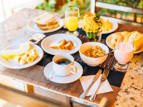 a table topped with plates of food and cups of coffee at VELINN Pousada Face Norte in Ilhabela