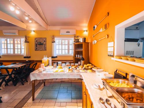 uma grande cozinha com uma longa mesa com comida em VELINN Pousada Face Norte em Ilhabela