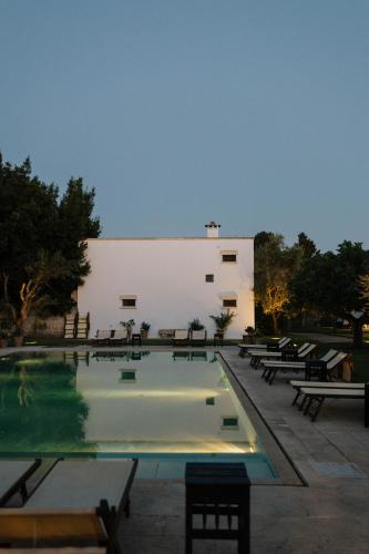 a swimming pool with benches and a building at Masseria Montelauro in Otranto