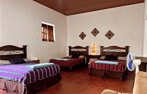 um quarto com duas camas e um sofá num quarto em El Extranjero Hostal em Antigua Guatemala