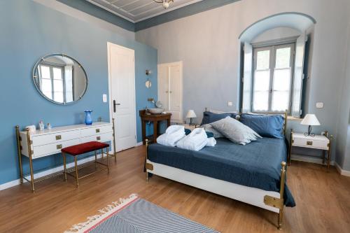 a blue bedroom with a bed and a mirror at ENGLEZENA'S GUESTHOUSE in Leonidion