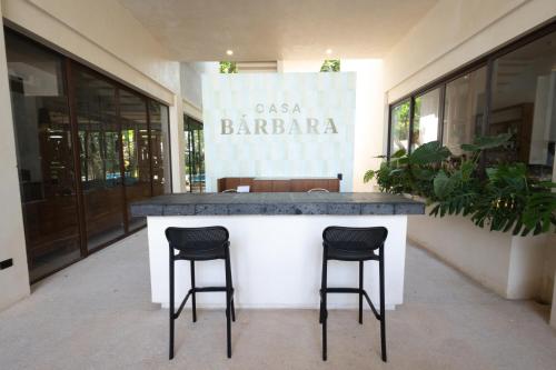 a bar with two stools in front of a building at Hotel Casa Barbara Holbox in Holbox Island