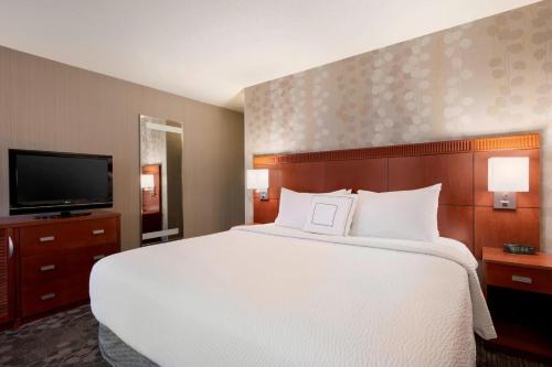 a bedroom with a large bed and a flat screen tv at Courtyard Akron Fairlawn in Montrose