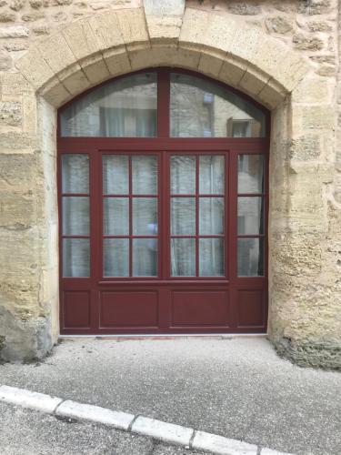 una porta rossa del garage in un edificio in pietra di Studio au Piano a Saint-Siffret