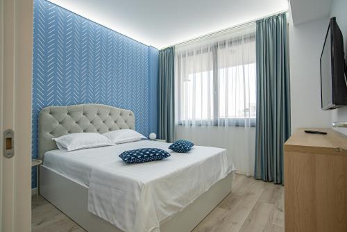 - une chambre dotée d'un lit avec un mur bleu dans l'établissement GooApartments Five, à Mamaia Nord – Năvodari