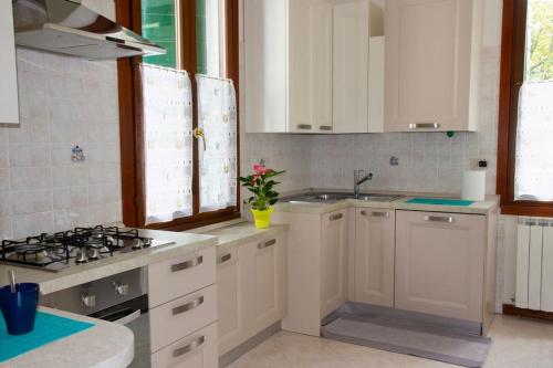 a kitchen with white cabinets and a sink at Isola del Lido, Luminoso, immerso nel verde, per 5 in Venice-Lido