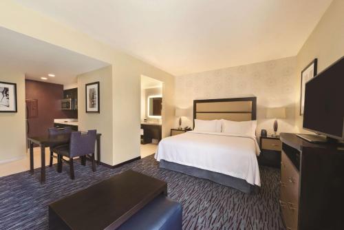um grande quarto de hotel com uma cama e uma secretária em Homewood Suites Mobile em Mobile