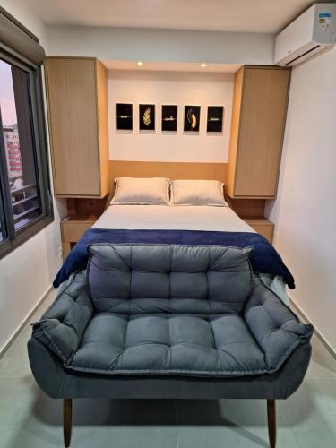een slaapkamer met een bed met een blauwe leren bank bij Lindo Studio NOVO no JP Redenção - Rofftop com vista espetacular in Porto Alegre
