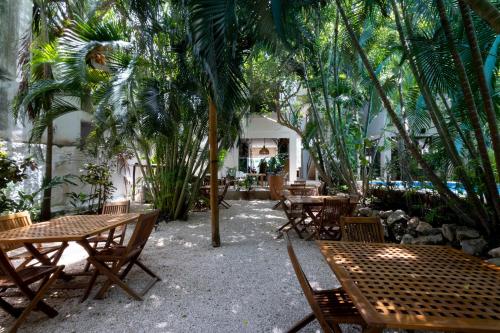 un patio con mesas, sillas y palmeras en Hotel Casa Barbara Holbox en Holbox Island