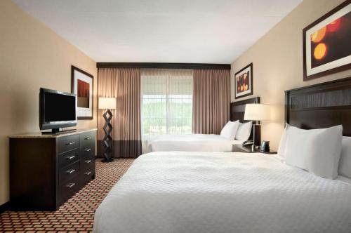 a hotel room with two beds and a flat screen tv at Embassy Suites by Hilton Jackson North Ridgeland in Ridgeland