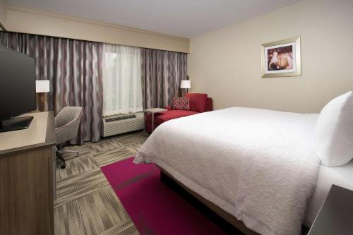 a hotel room with a bed and a flat screen tv at Hampton Inn Louisville East Hurstbourne in Louisville